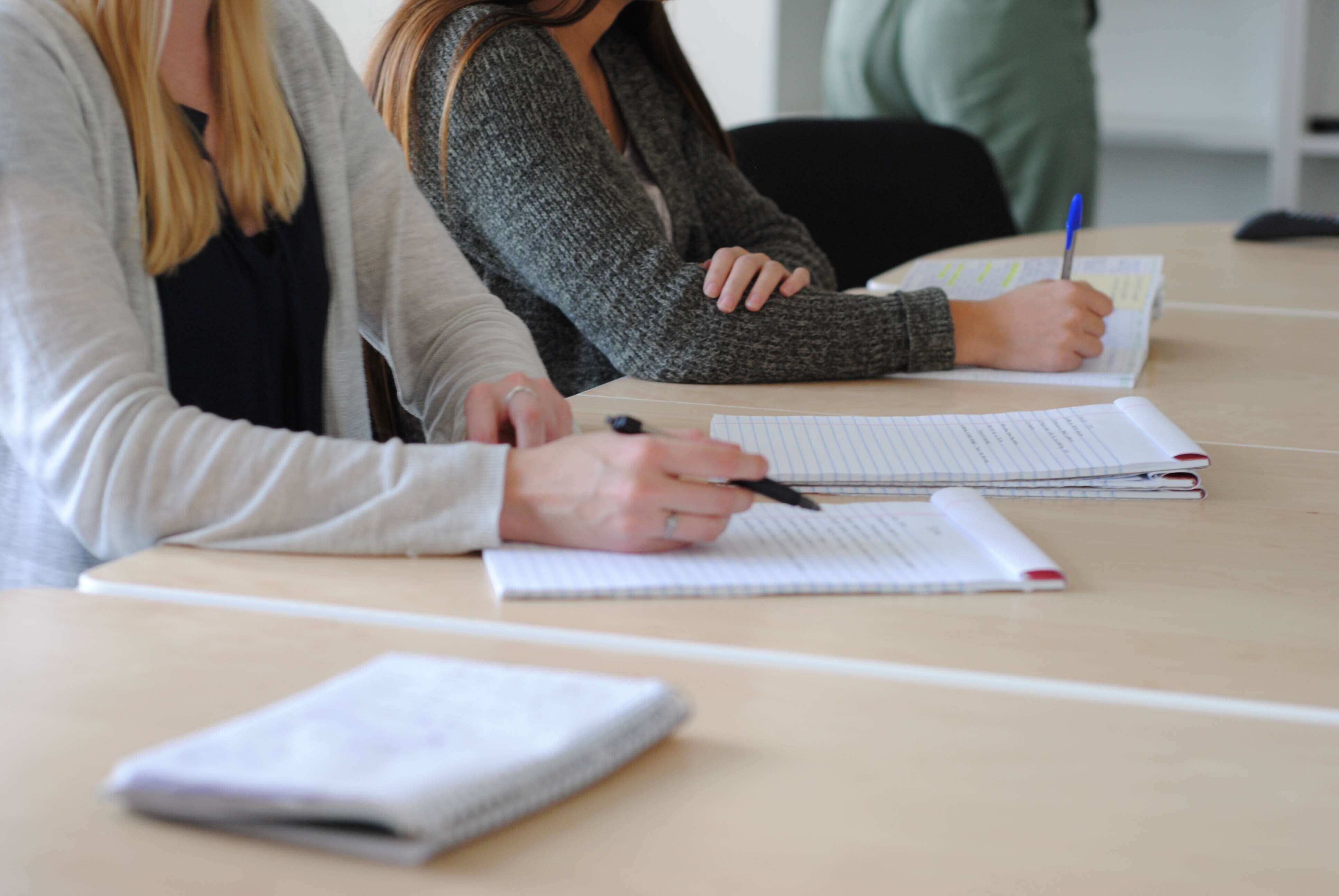 Students studying together at a desk, preparing for the TOEIC test with notes and study materials.